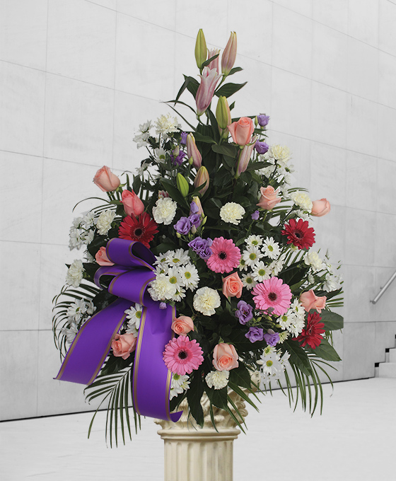 Centro funerario premium con lilis rosas y cinta morada